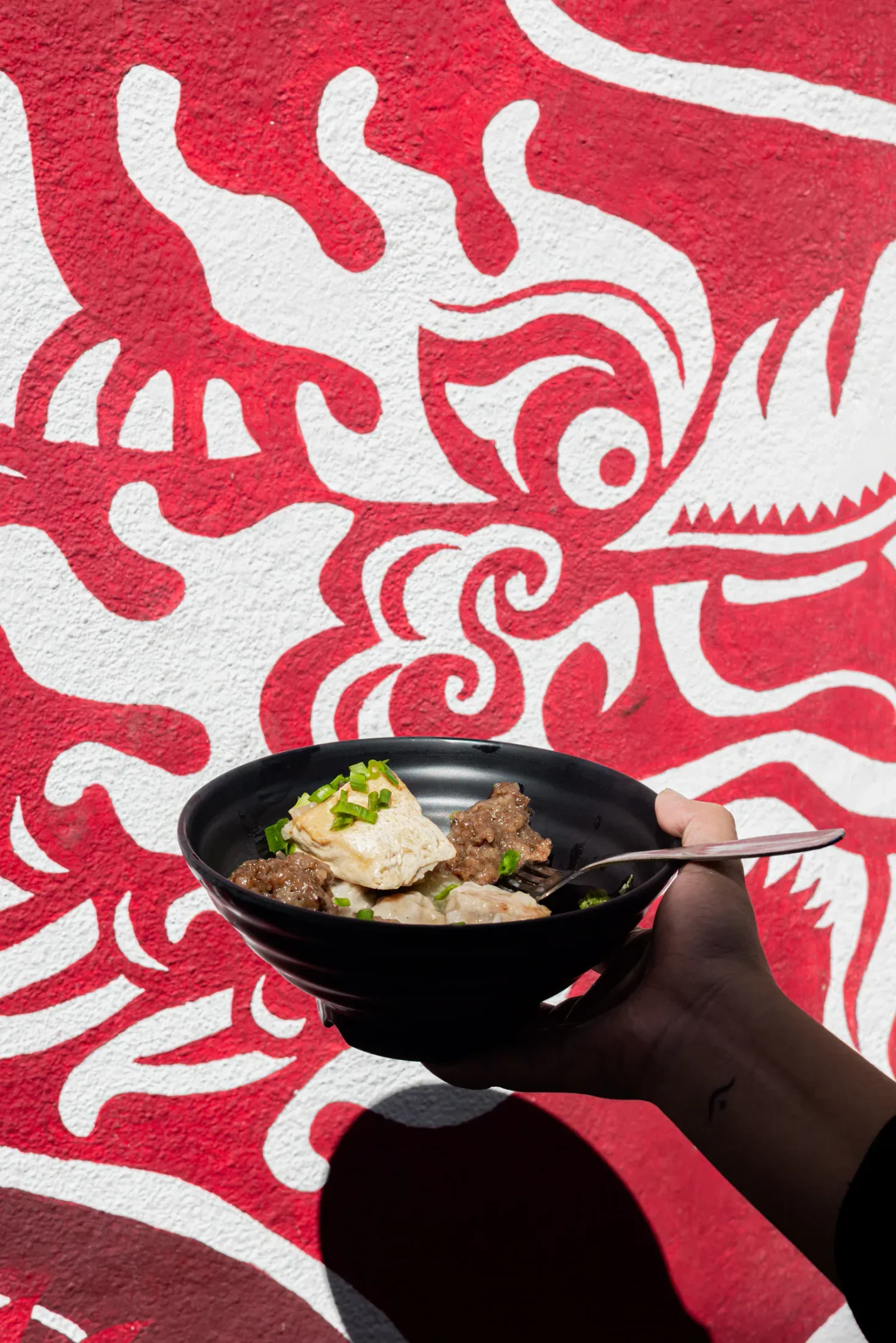 Un bol de cuisine sino-mauricienne devant un mur peint à Chinatown